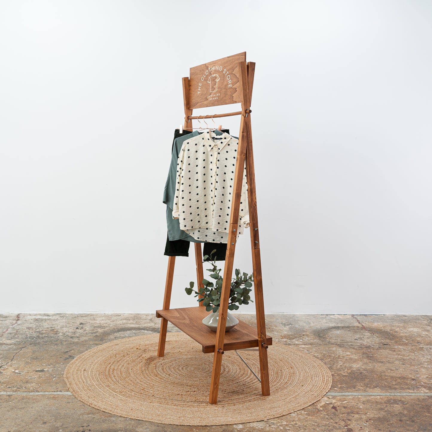 Coffee-colored freestanding clothing display stand with horizontal bar