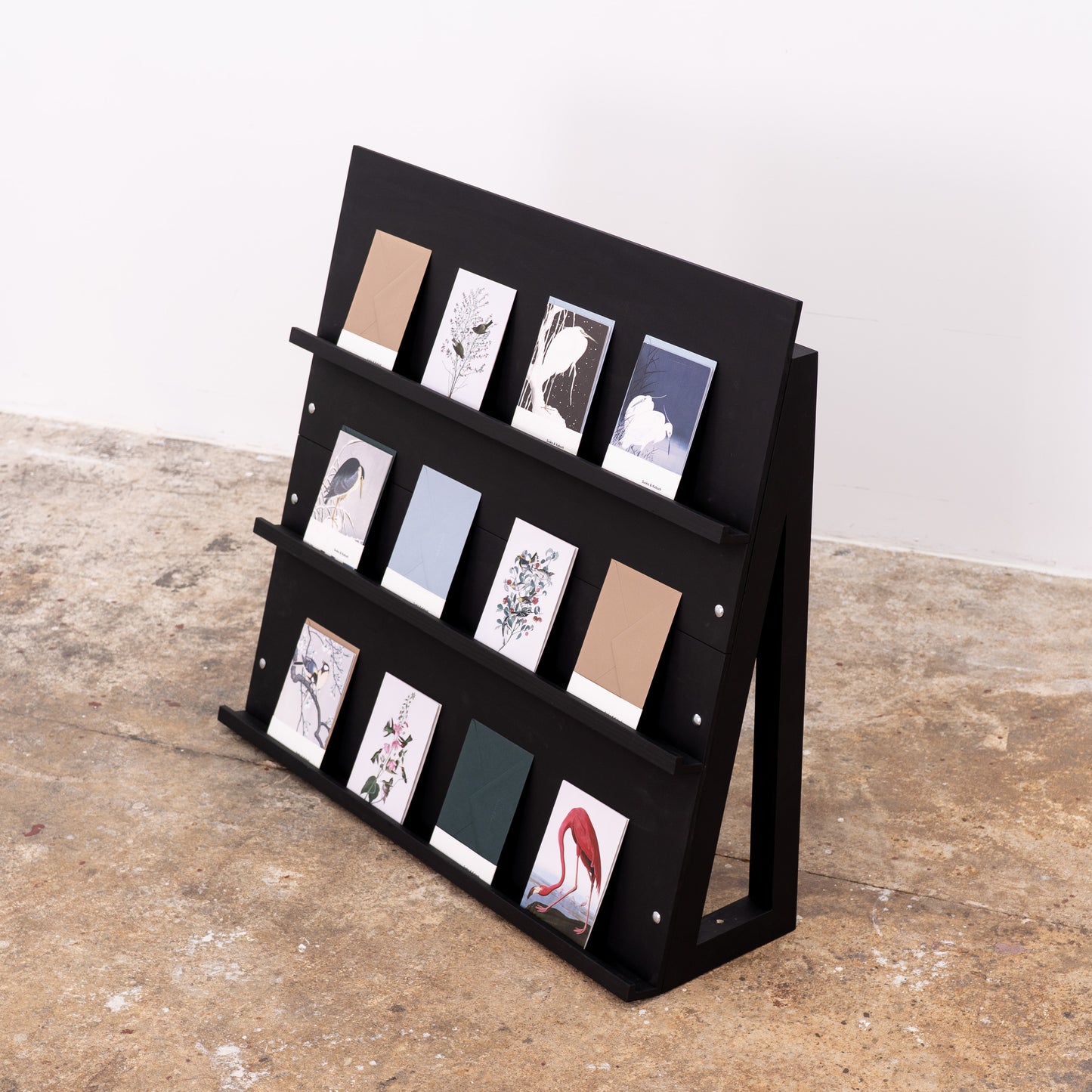 Angled black shelf styled with various-format printed materials