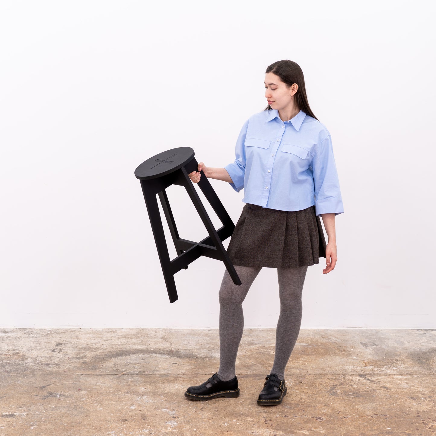 Portable black counter-height stool displayed on wooden floor