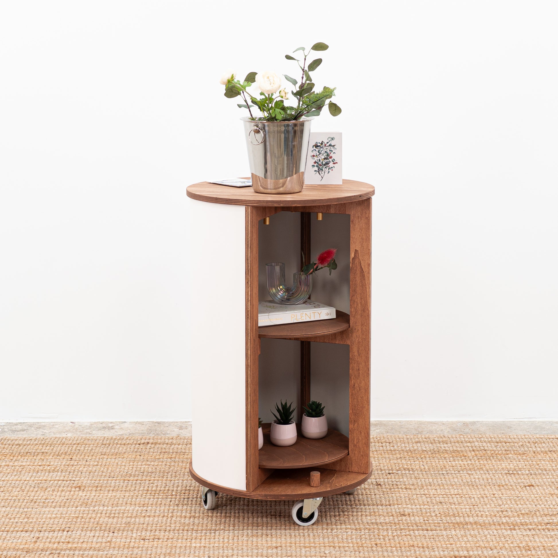 Customizable round host stand in white with lockable wheels, offering functional storage and display space for products at events.