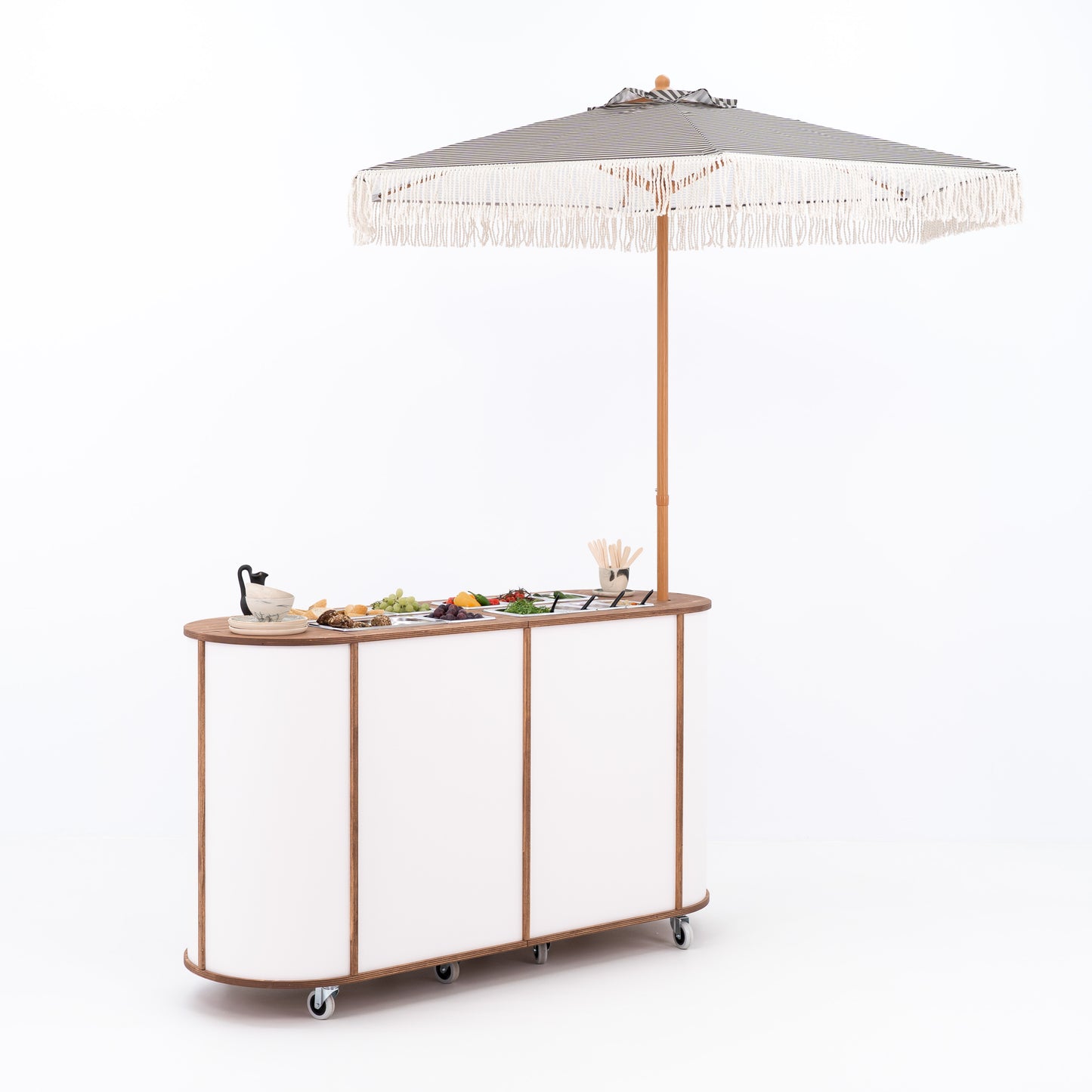 Mobile charcuterie bar with food displayed under umbrella