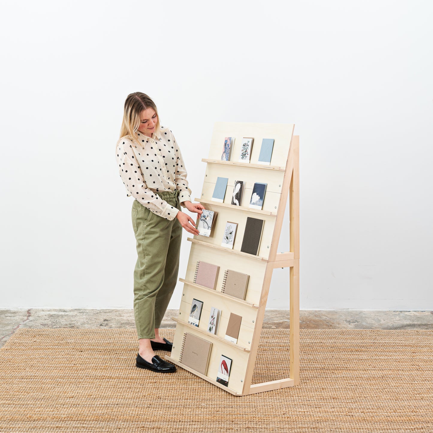 Natural wood magazine stand with postcards and notebooks