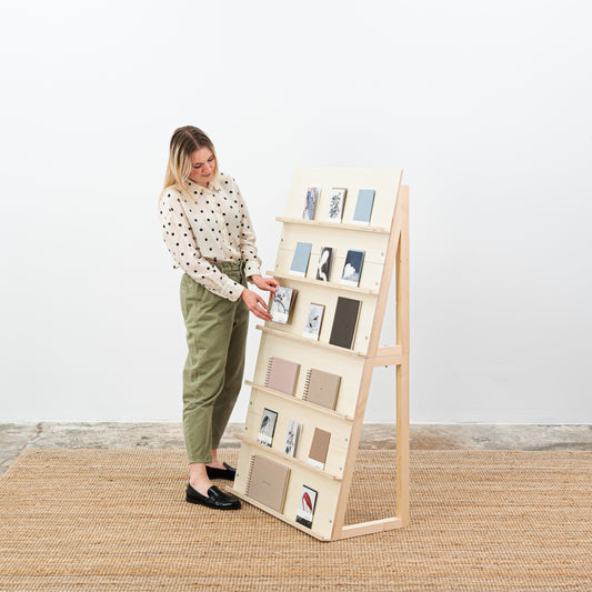 Natural wood magazine stand with postcards and notebooks