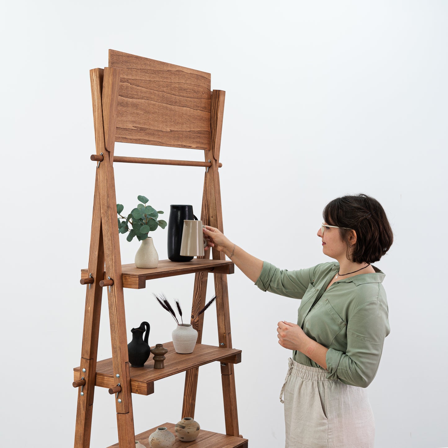 Portable wooden shelf with home décor items on tiers