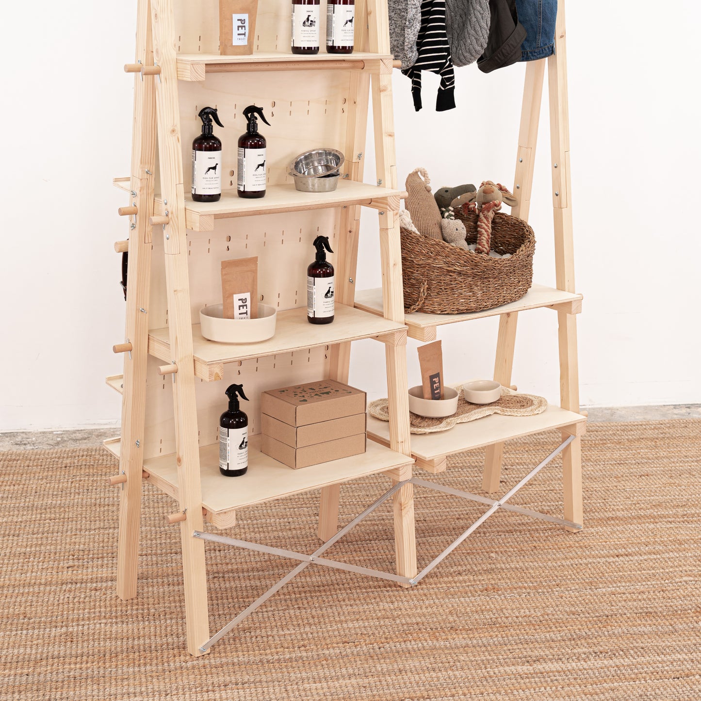 Portable display stand with pegboard hooks, adjustable shelving, and garment rod