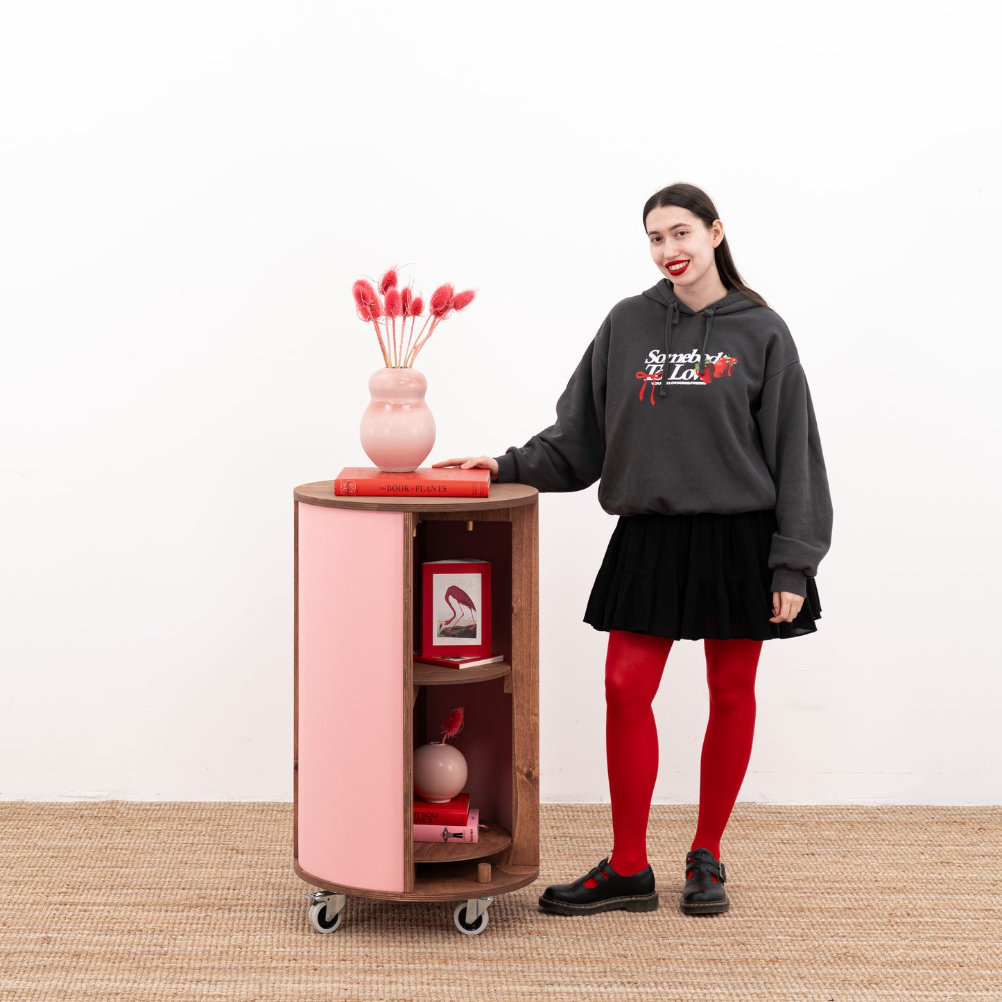 Pink round host stand with decorative items on top, showcasing customizable design options.