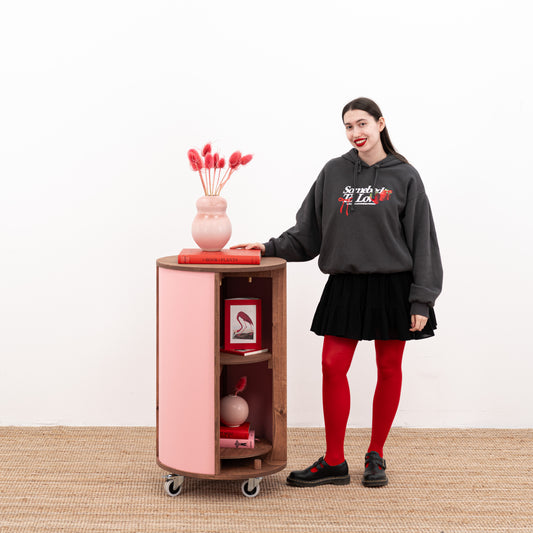 Pink round host stand with decorative items on top, showcasing customizable design options.