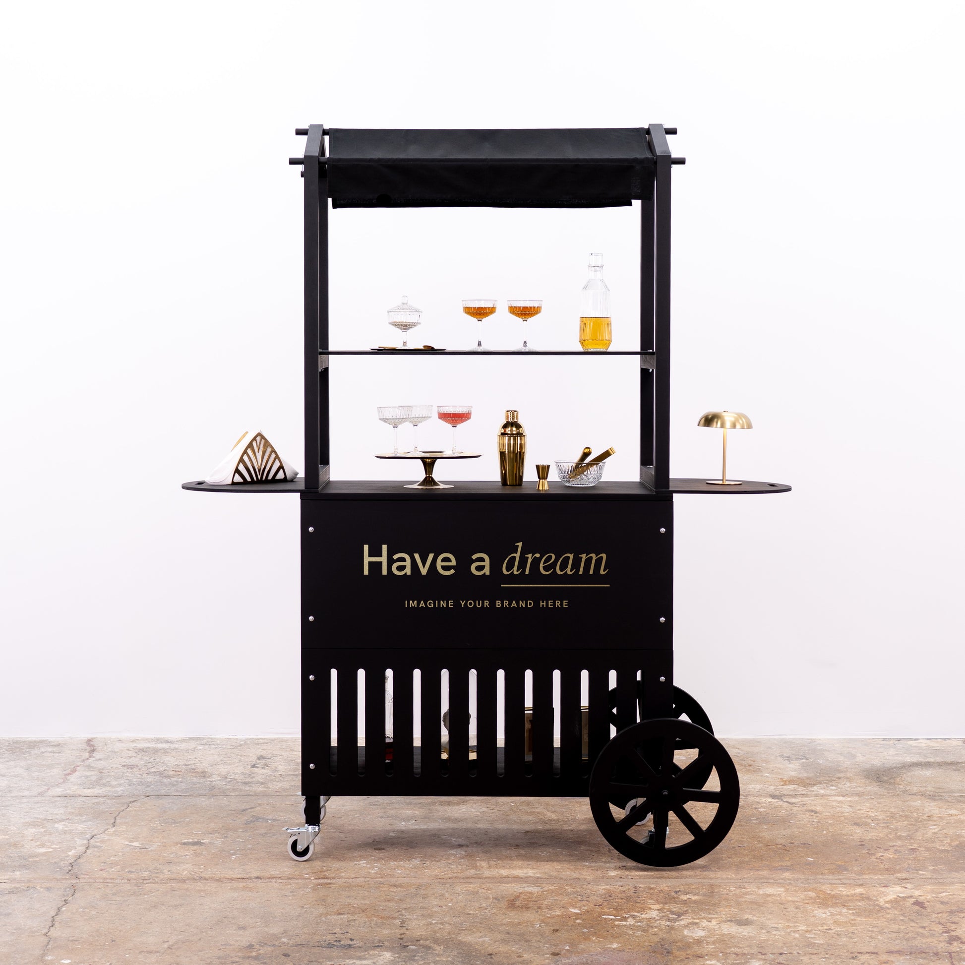 Black mobile cart with elegant glassware and gold accents, featuring the 'Have a dream' logo.