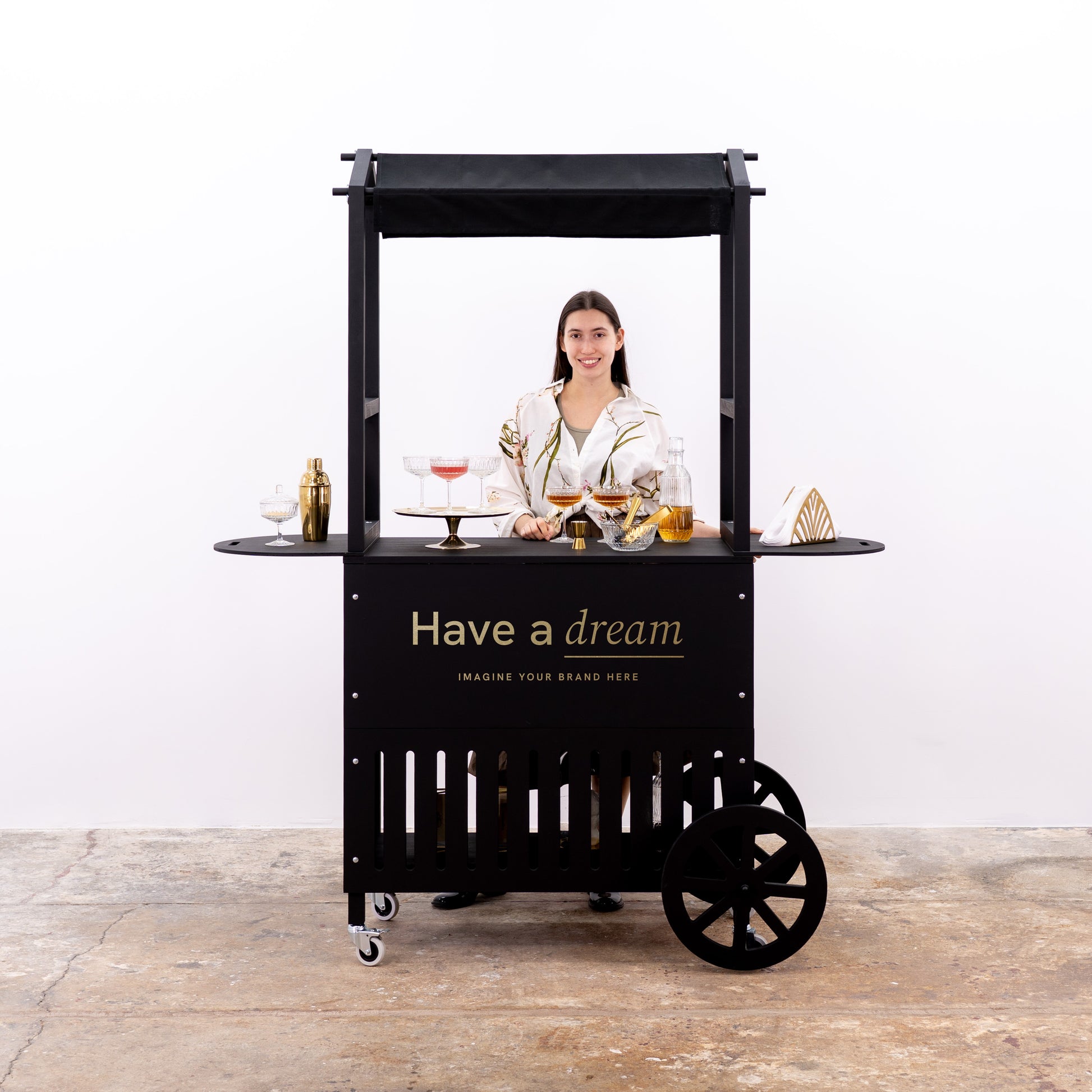 Minimalist cart setup with glass drinkware and gold bar tools, showcasing a customizable display space.
