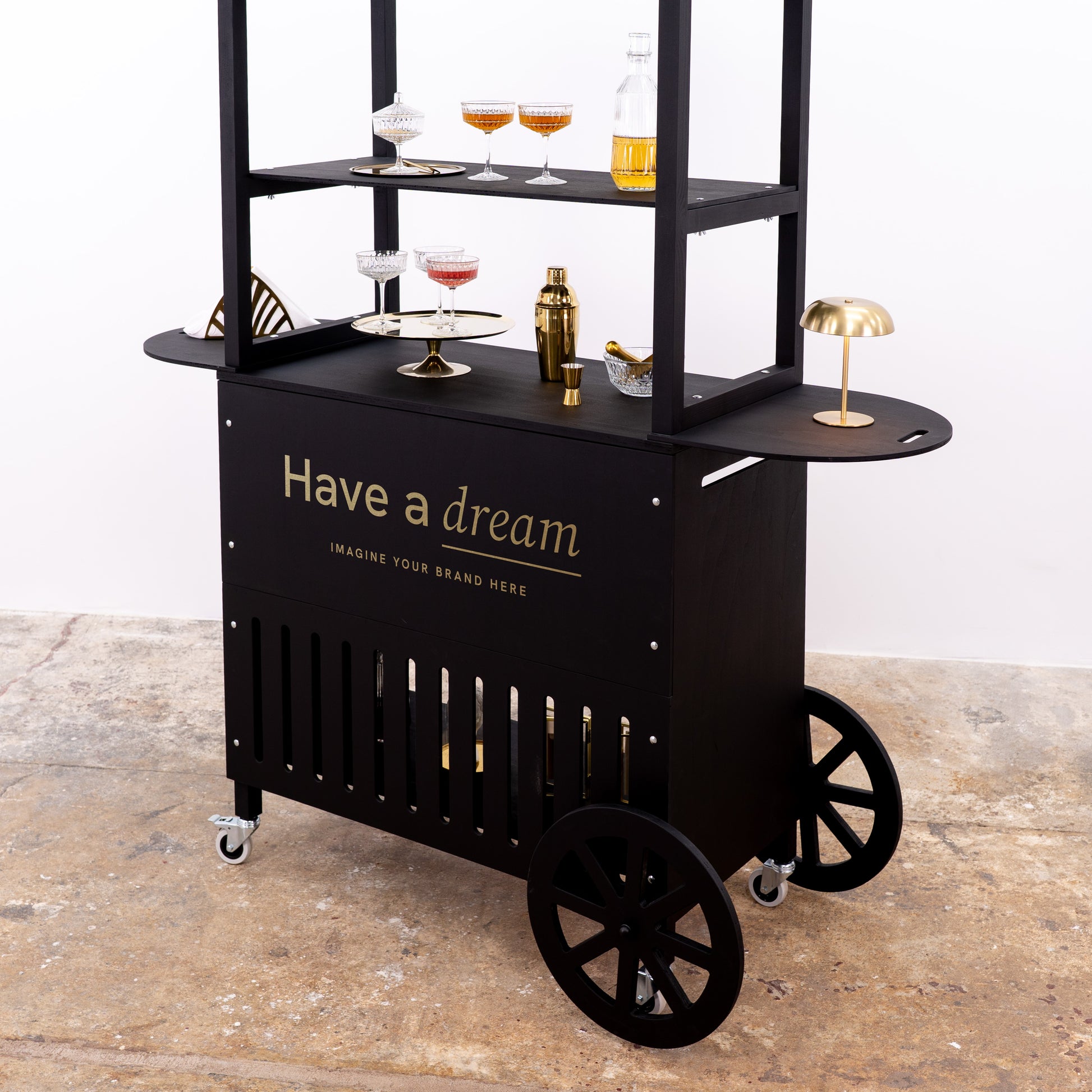 Sleek black bar cart featuring stylish glassware, gold cocktail tools, and a personalized logo for branding.