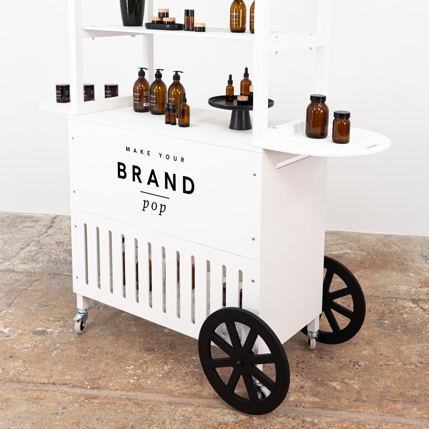 Functional white cart with spacious shelving, perfect for merchandising and product displays at trade fairs.