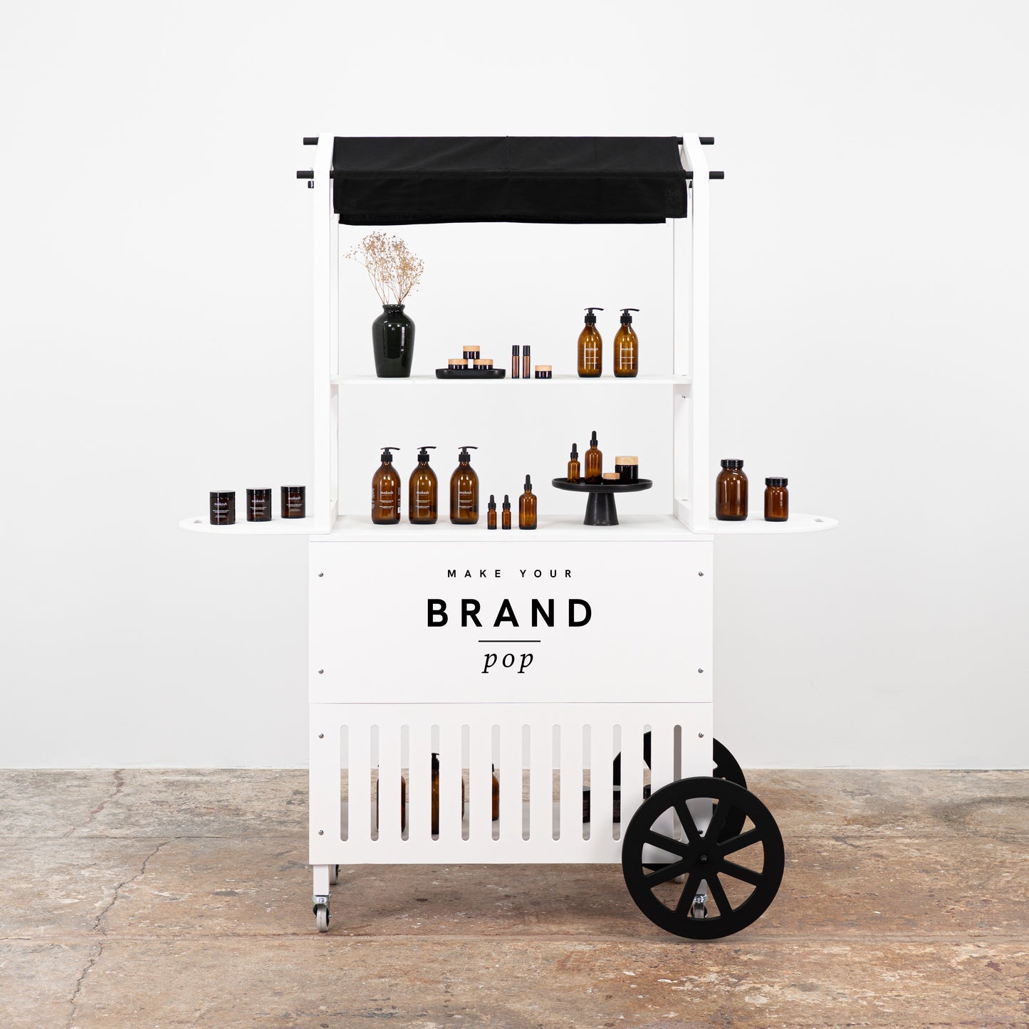 Minimalist white bar cart with product displays, showcasing skincare and cosmetic items, ideal for trade shows and pop-up shops.