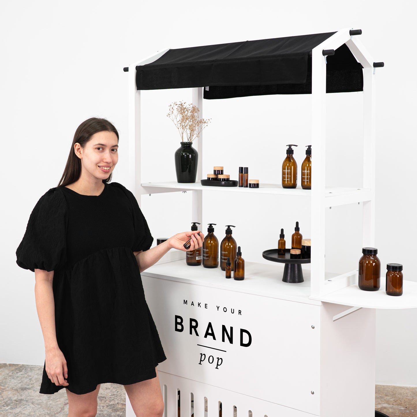"Modern white cart with black wheels, showcasing a selection of skincare products and offering a personalized branding space.