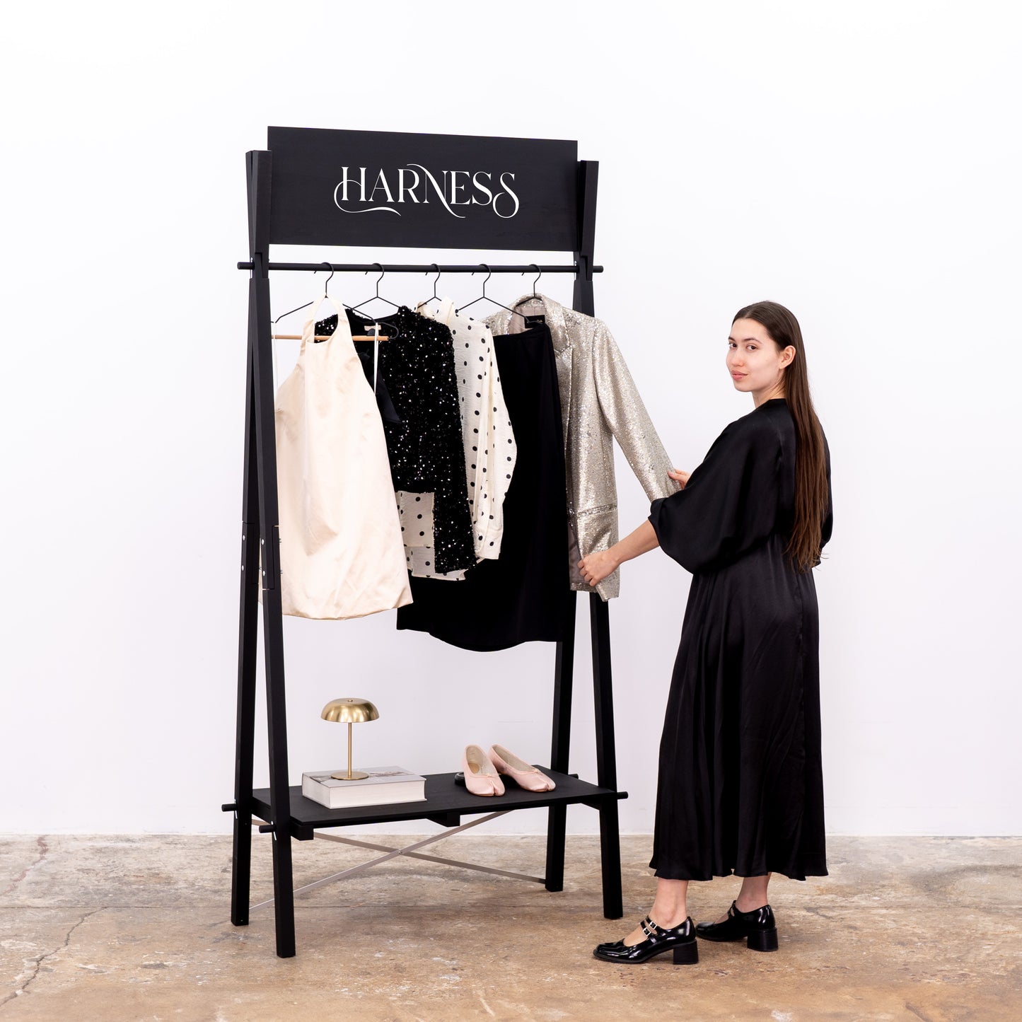 Black wooden clothing rack with shelf and branded sign