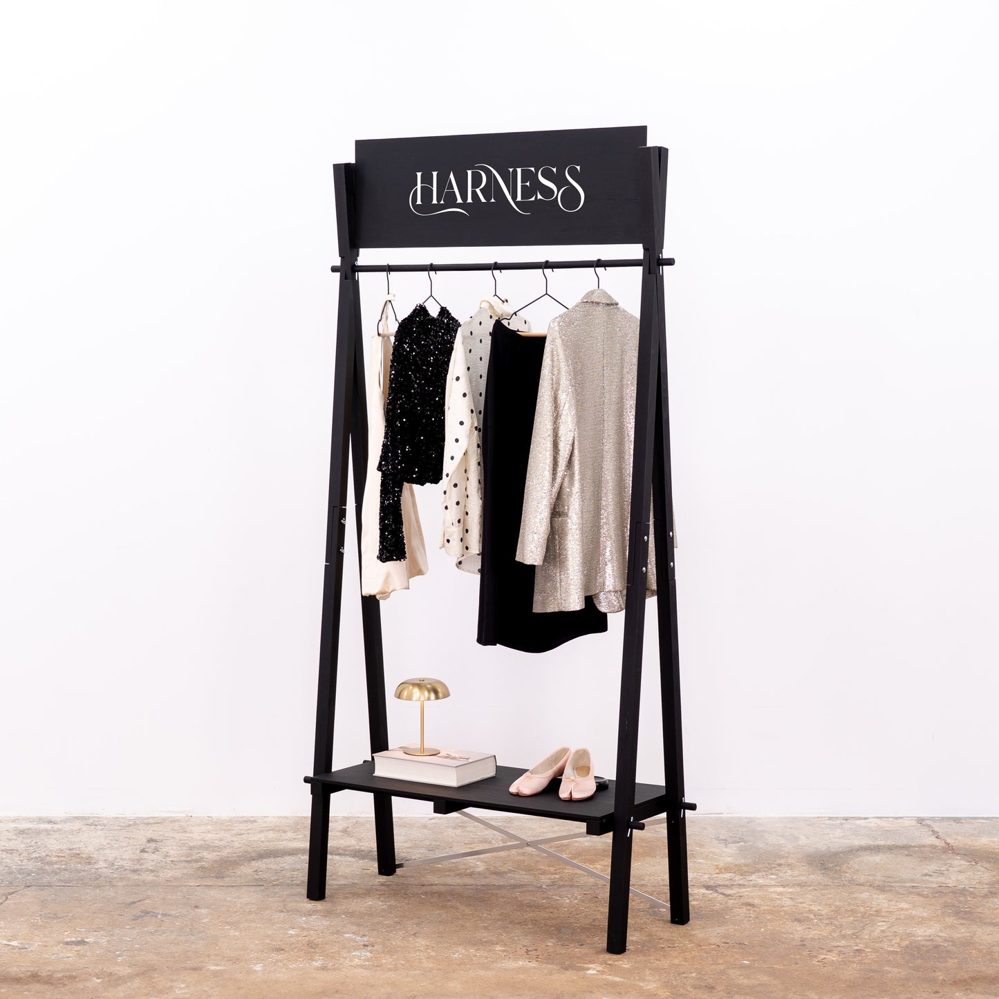 Wooden clothing rack with shelf in black finish displaying bathrobes and accessories