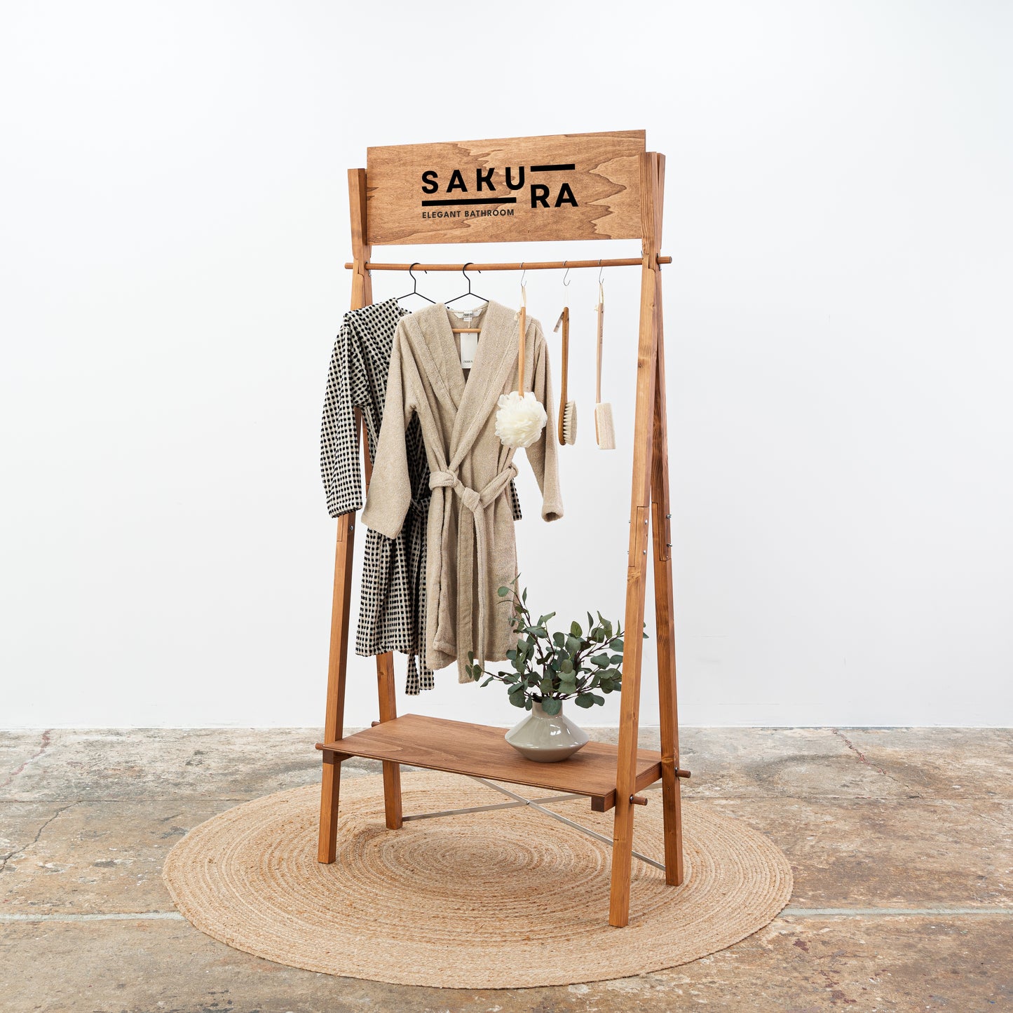 Wooden clothing rack with shelf in coffee finish displaying bathrobes and accessories