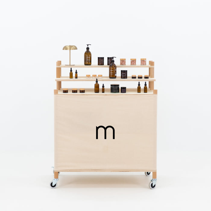 Front view of wooden checkout stand with branded fabric panel and tiered display shelves
