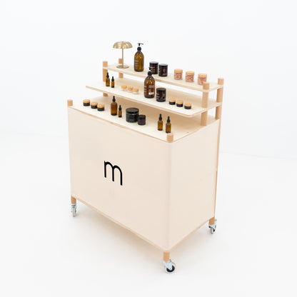 Side angle of portable checkout counter showing raised product shelves and rear storage space