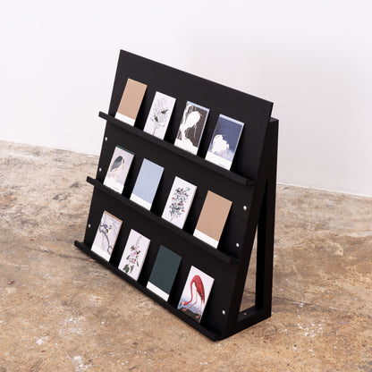 Angled black shelf styled with various-format printed materials