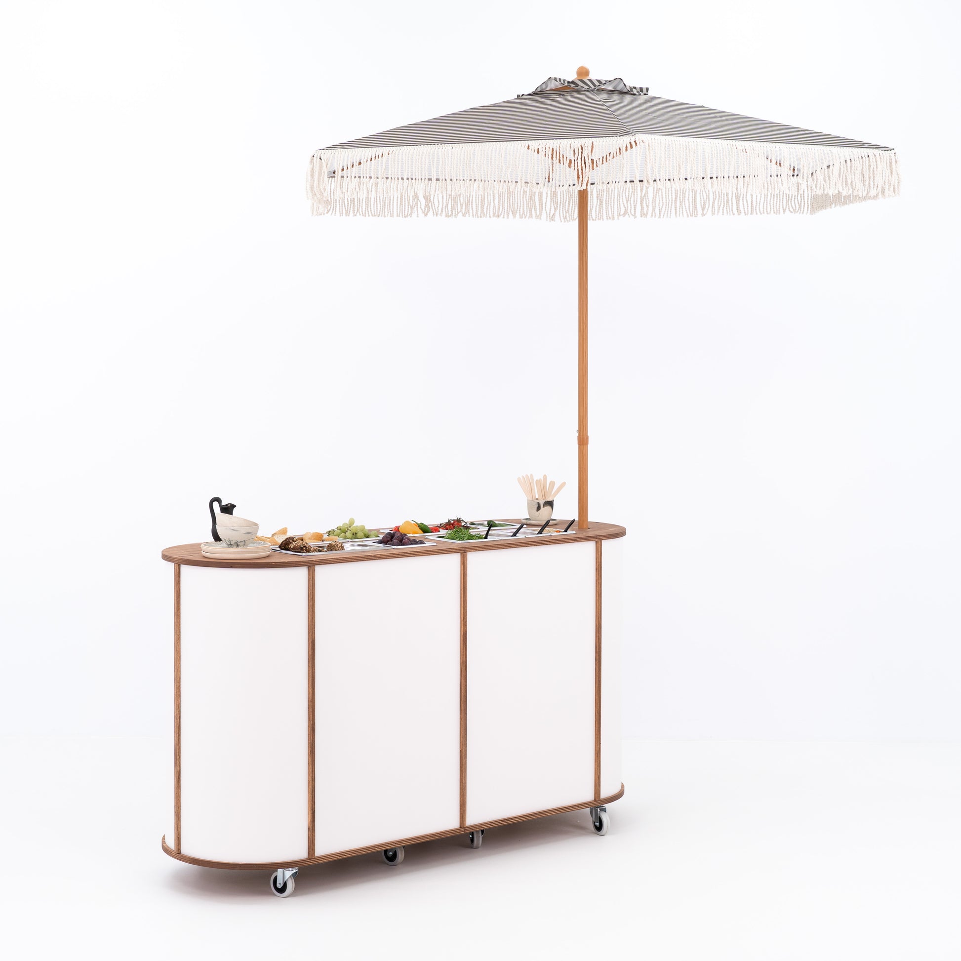 Mobile charcuterie bar with food displayed under umbrella