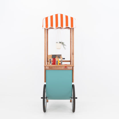 Side view of food and beverage event cart with striped canopy and large wheels
