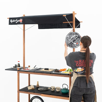 Person hanging the round logo board on the BC-09-W-ML market stall cart set up as a sushi station
