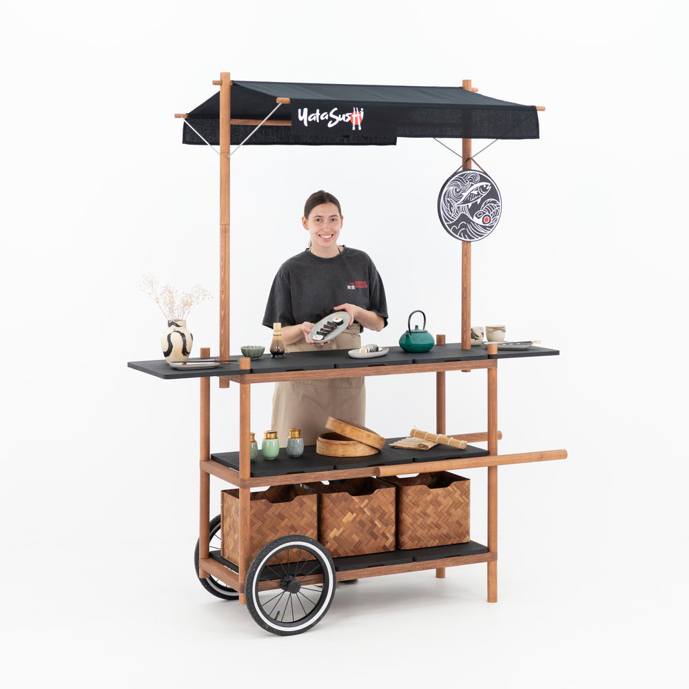 Chariot événementiel avec toit BC-09-W-ML utilisé en bar à sushi personnalisé, avec une personne présentant un plat
