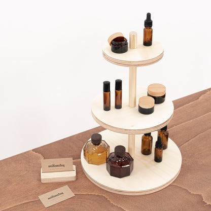 Natural wood riser featuring three tiers for showcasing a range of products, with cosmetics arranged on each level.