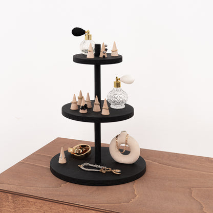 Three-tier tabletop display stand with black varnish, showcasing jewelry and cosmetics.