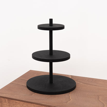 Close-up view of the tabletop display stand with matte black varnish, designed for displaying perfumes and candles.