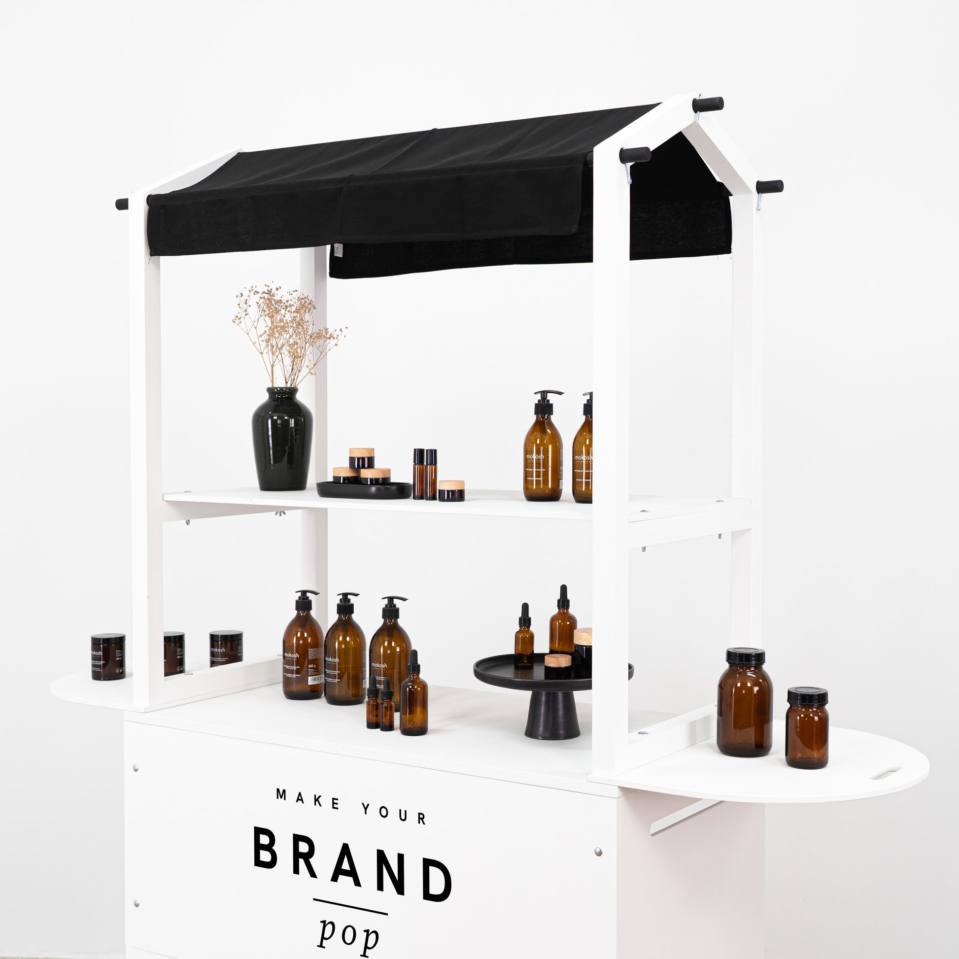 Elegant white display cart featuring branded logo, displaying amber bottles and cosmetics in a clean and stylish setup.