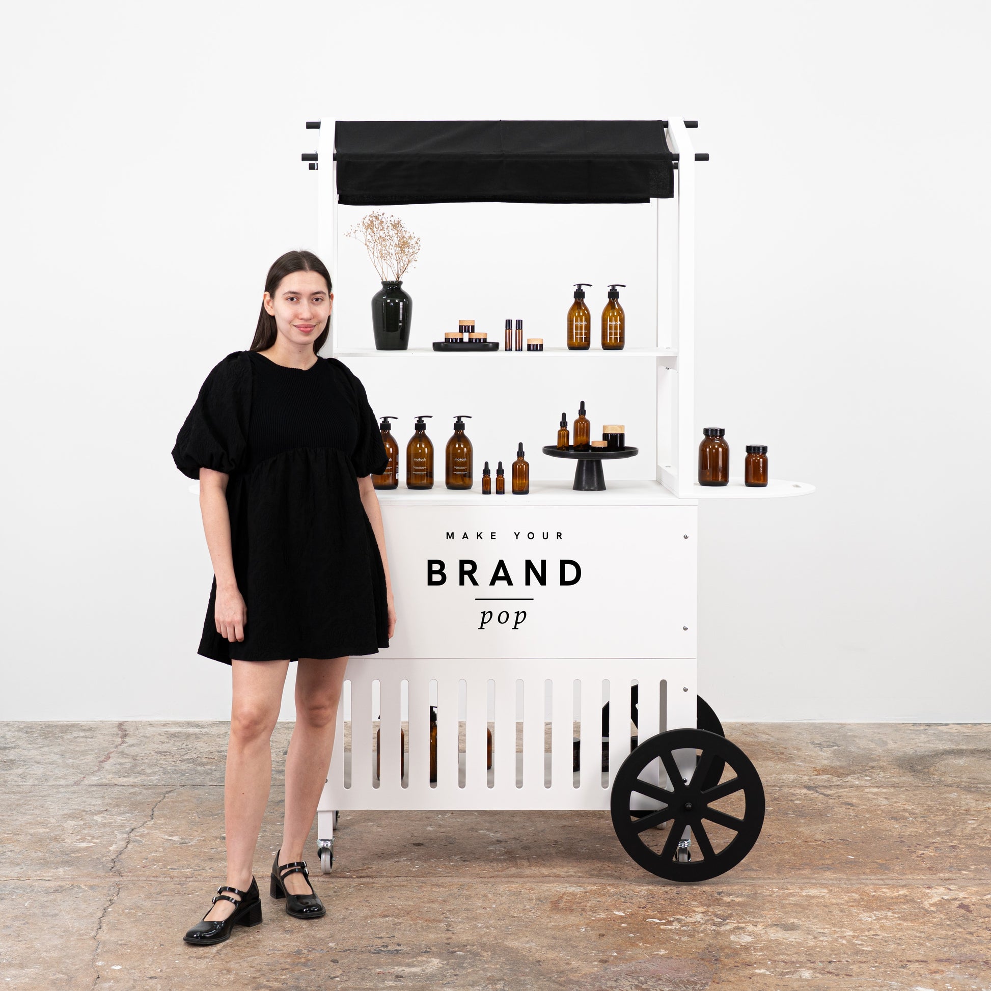 Portable white cart with a professional design, featuring skincare products and branding space for events and exhibitions.