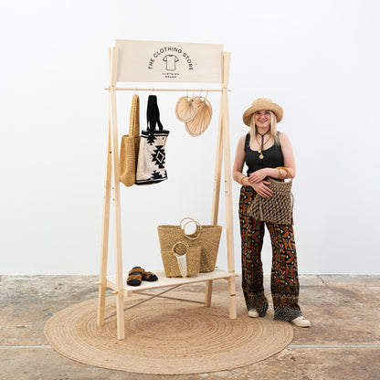 Retail display rack in light natural tone with clothing and accessories